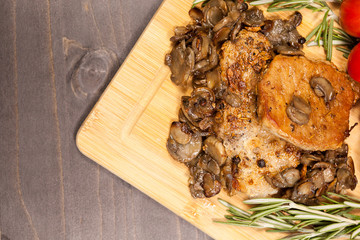 Top view on grilled pork and mushrooms next to cherry tomatoes on wooden board