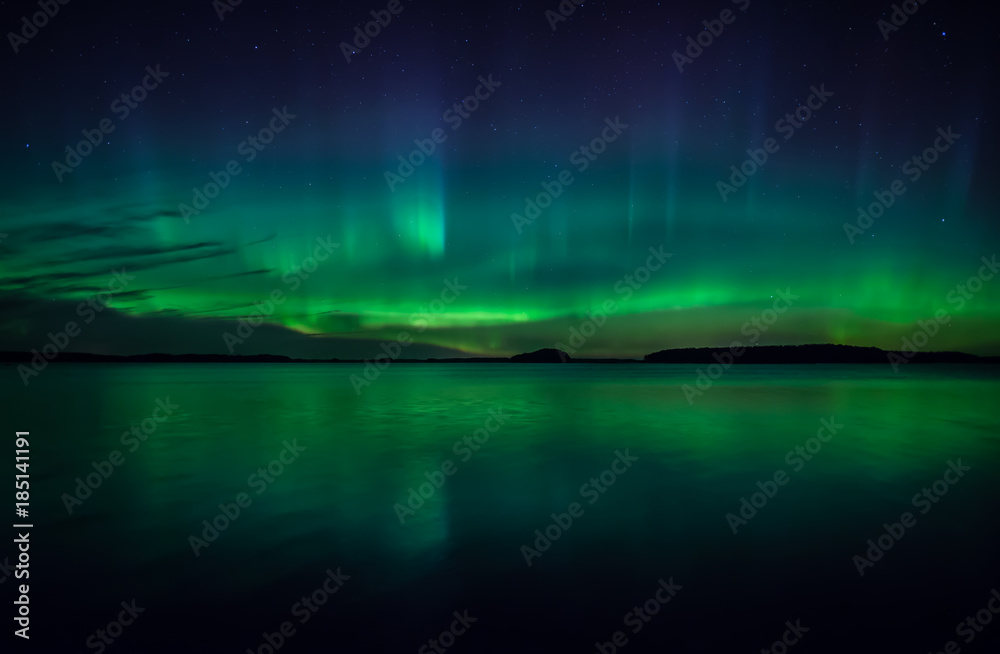 Wall mural northern lights dancing over calm lake in farnebofjarden national park in sweden
