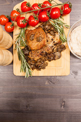 Over top view on grilled pork and mushrooms next to oregano and bean paste on wooden board on wooden table