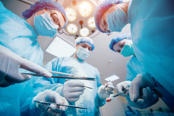 Group of surgeons in operating room with surgery equipment.