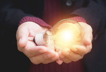 Hand of businesswomean holding light bulb for idea or success or solar energy