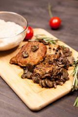 Hot grilled pork steak, mushrooms cherry tomatoes and a plate with bean paste on wooden plate on a table