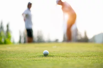 Poster Golfbalbenadering van het ruim op de green. Paar golfspeler die golfbal op de achtergrond zet. Levensstijlconcept. © freebird7977