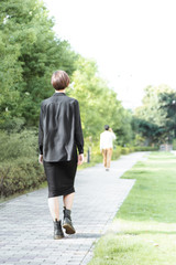 新緑が爽やかな歩道を歩く男女