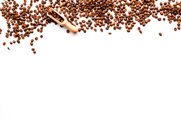 Scattered coffee beans and beans in scoop on white table top view copyspace. Coffee background.
