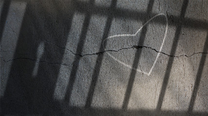 Heart Drawn on a Cracked Concrete Wall Under jail Bars