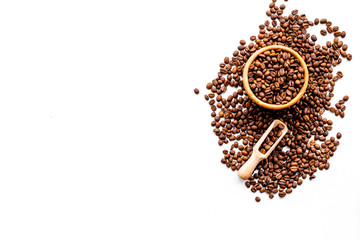 Fresh roasted coffee beans in bowl and scoop on white table top view copyspace. Coffee background.