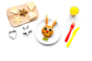 Funny breakfast for children. Meal with cheesecake in shape of hare. White background top view