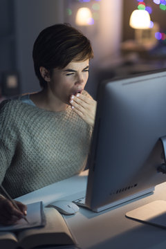 Woman working at night and yawning