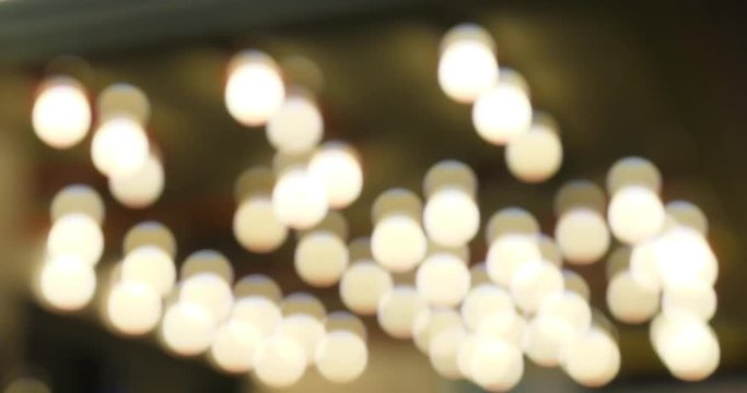 Blurred theatre lights blinking on the ceiling of a city marquee at night.  	