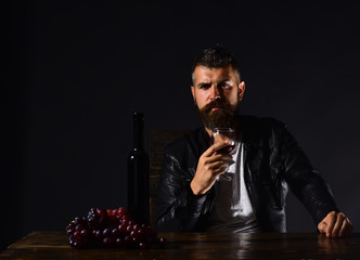 Man with beard holds glass of wine on brown background