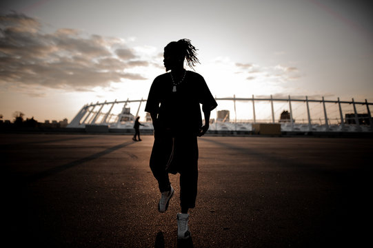 African guy with dreadlocks dancing on the background of sunset
