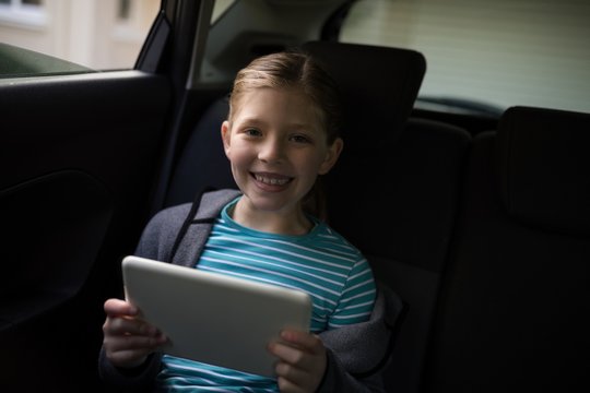 Teenage girl using digital tablet in the back seat of car