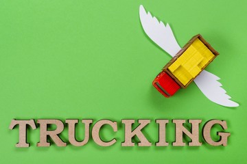 Abstract picture of a truck with wings and a word of trucking. Green background. Cargo transportation of the future