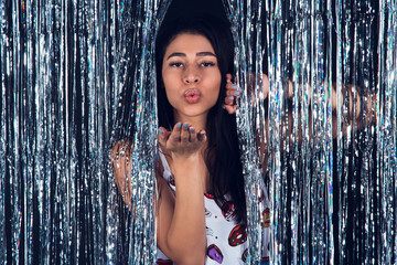 Kiss from a beauty. Beautiful young woman blowing kiss to you and looking at camera while standing against black background