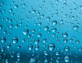 water drops on glass, a vivid image of rain drops on blue background, colorful background texture