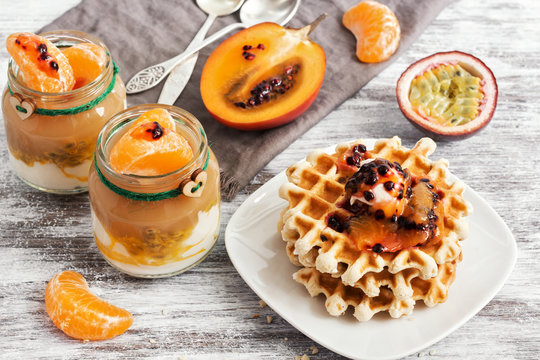 Homemade waffles with fresh tamarillo on a white wood surface. Yogurt with fresh fruits. Selective focus
