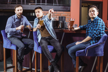 Young men with a beer watching the match in the bar.
