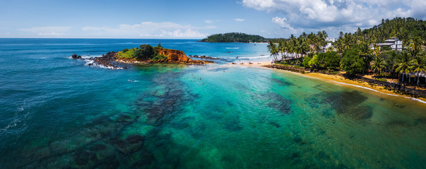 Aerial panorama of the tropical beach and clear sea with coral reefs in the town of Mirissa, Sri Lanka
