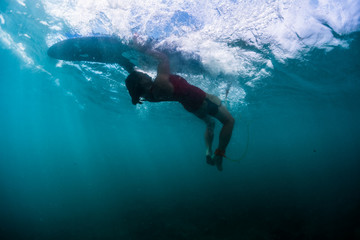 Surfer performs trick named Turtle Roll to pass the breaking wave