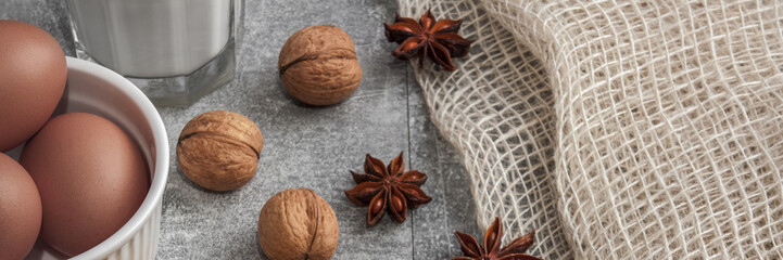 Panoramic top view of sweet yeast with curd, walnuts, stars of anise, fresh eggs, a glass of milk and jute on a concrete counter