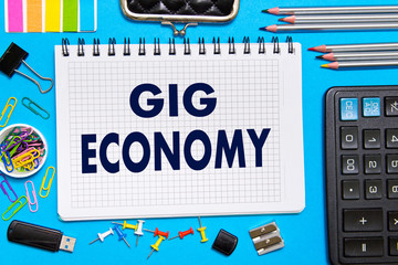 Notebook with Notes GIG ECONOMY office tools  on a blue background . Concept GIG ECONOMY