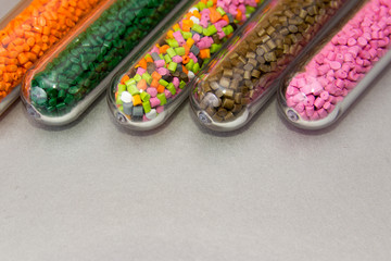 Plastic pellets .Polymeric dye in test tubes on gray background.