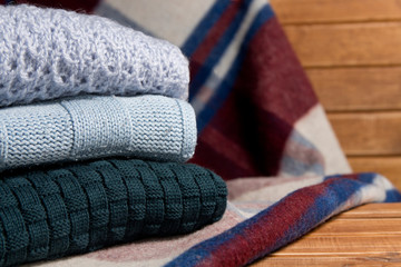 Stack of cozy knitted warm sweater and a blanket . Sweaters in retro Style