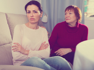 Sad mature female and daughter at sofa after quarrel