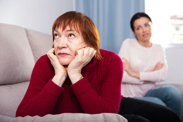 Unhappy women sitting at sofa after conflict at home