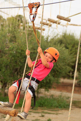 Cute boy enjoying a sunny day in a climbing adventure activity park. Boy at climbing activity in high wire forest park.