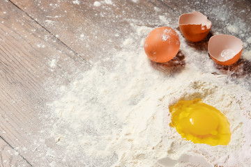 The top view of an egg, beaten into flour, cooking dough against the background of a wooden table.