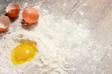 The top view of an egg, beaten into flour, cooking dough against the background of a wooden table.