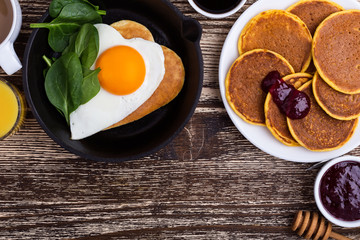 Valentine's day breakfast with  heart shape fried egg in cast iron skillet and pancakes