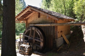 Restored or renovated old mediaeval wooden watermill or water mill in Austrian alps or alpine region tirol or carinthiha powered by mountain stream. Traditional industrial building in alpine region.