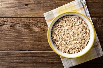 Oat flakes in bowl on dark wooden table