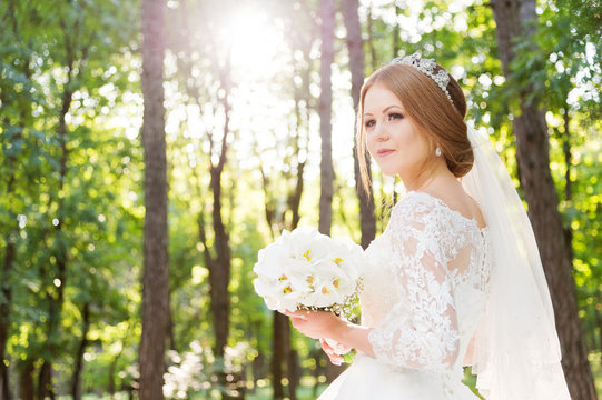 Portrait of a beautiful bride in a white dress and a bouquet of flowers in her hands