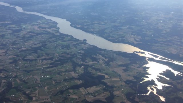 Aerial view from jet flying over the Susquehanna River, small farm fields, homes and woodland in Pennsylvania, USA. Real time 4K.