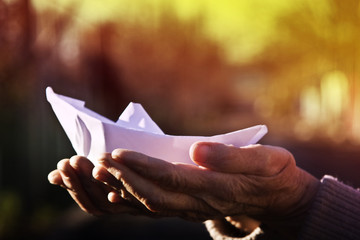 Paper boat in old wrinkled hands of my grandmother