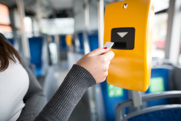 Young woman hand inserts the bus ticket into the validator, validating and ticking - obrazy, fototapety, plakaty