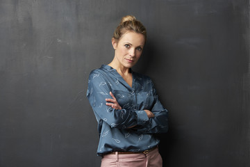 Obraz premium Studio shot of a confident mature woman looking at camera while standing against at gray background.