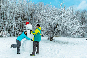 couple making snowman in city park