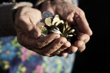 Coins in old wrinkled hands of grandmother close-up