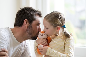 Father and daughter kissing soft toy