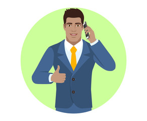 Businessman talking on the mobile phone and showing thumb up