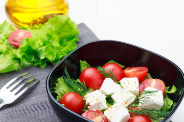 Salad with vegetables, cheese or tofu, tomatoes, herbs on white background.