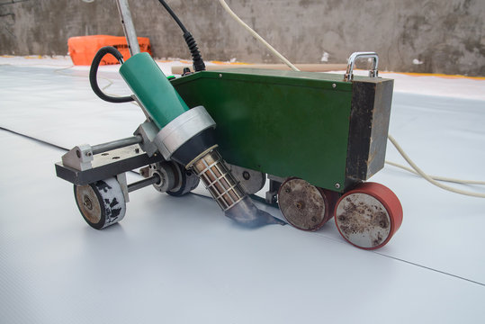 Waterproofing and insulation at construction site, roof sealing process of synthetic pvc membrane with Automatic plastic welder. New protection technology.