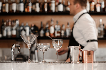 Clear and empty cocktail glasses arranged on the white bar counter