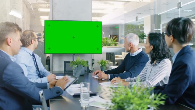 Diverse Group of Successful Business People in the Conference Room with  Green Screen Chroma Key TV on the Wall. They Work on a Company's Growth, Share Charts and Statistics.  RED EPIC-W 8K Camera.