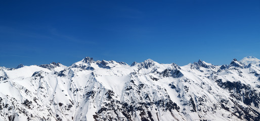Panorama of snow covered mountains and blue sky at sun cold day